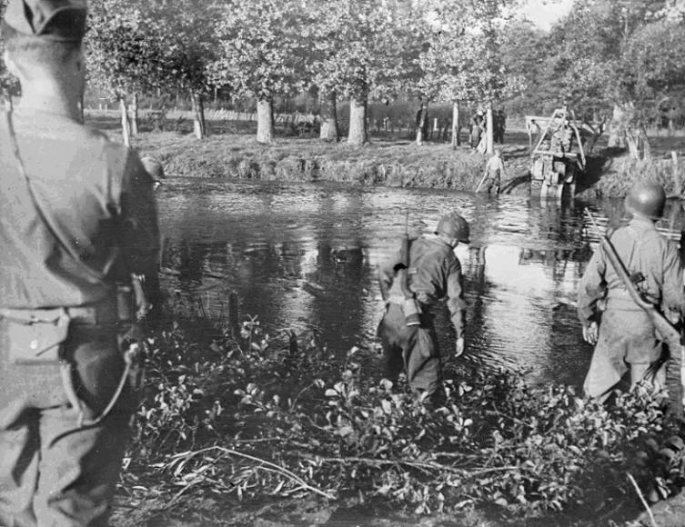 Soldats américains passant un cours d'eau dans la Manche lors de la progression de la IIIe armée américaine en Normandie, août 1944.