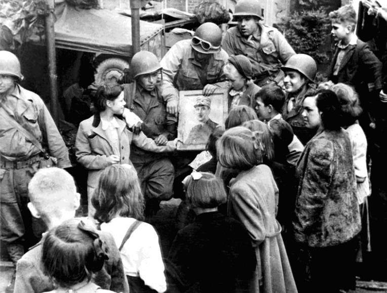 Soldats américains et enfants autour d'un portrait du général de Gaulle en Normandie, août 1944