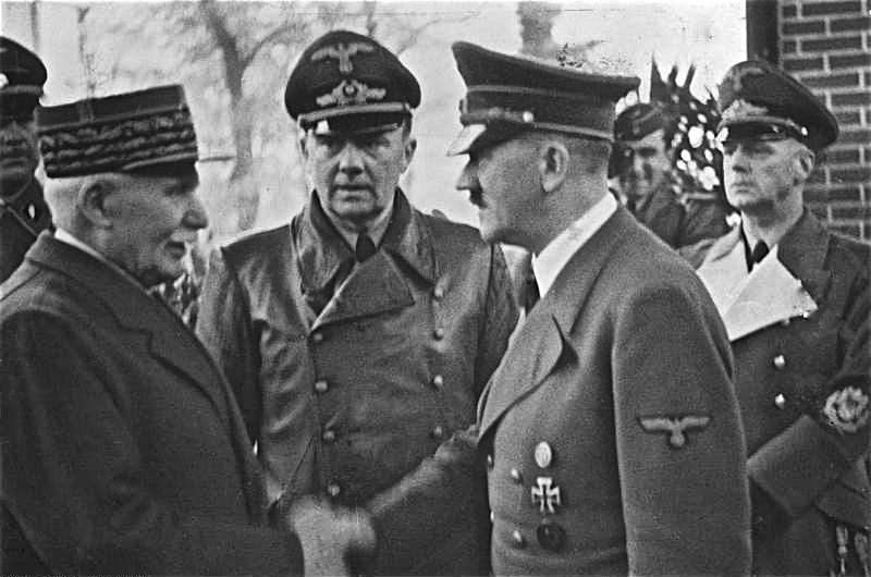 La poignée de main entre Philippe Pétain et Adolf Hitler, le 24 octobre 1940 à Montoire. À l'arrière-plan, le Dr. Schmidt, interprète de Hitler et sur la droite, von Ribbentrop, ministre . © Archives fédérales allemandes