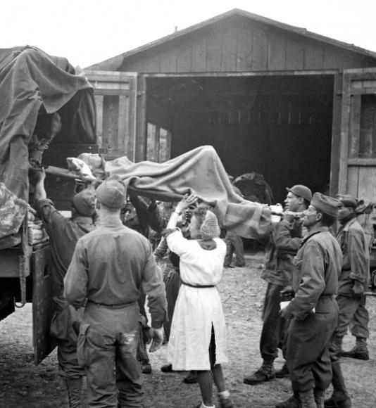 Des infirmières et des soldats français du 49e régiment d'infanterie apportents les premiers secours aux rescapés qui sont brancardés dans des camions qui les conduiront à l'hôpital ou les rapatrieront vers la France.