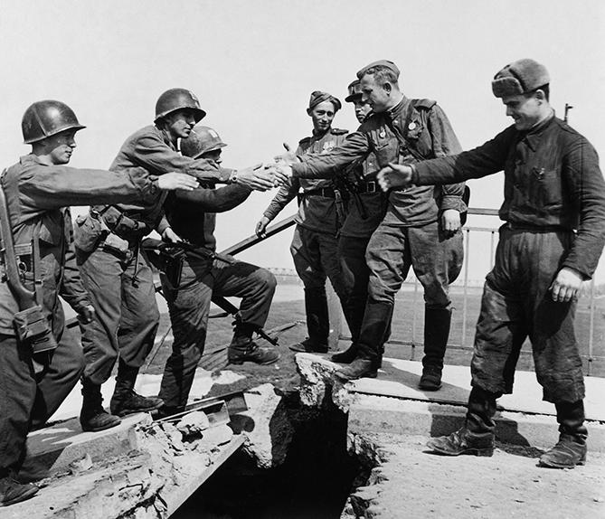 Soldats américains serrant la main à des soldats soviétiques, chacun d’un côté d’un pont en ruines sur l’Elbe. Torgau (Allemagne), 25 avril 1945.