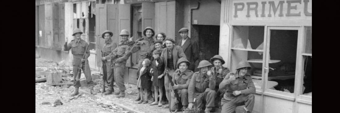 Erste britische Truppen in Caen posieren gemeinsam mit den Einwohnern vor den zerstörten Geschäften.